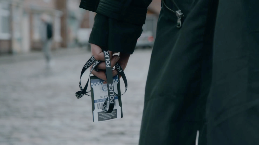 Lisa's police pass is wrapped around Carla's ring finger.